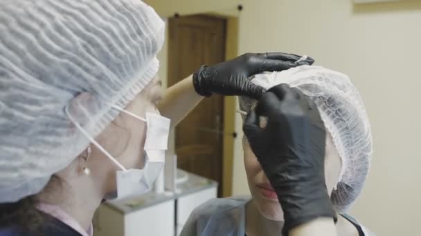 O empregado da clínica de cosmetologia faz manipulações na coloração das sobrancelhas — Vídeo de Stock