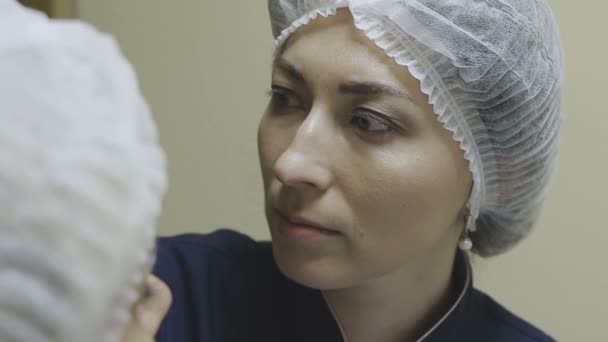 Сотрудник косметологической клиники перед процедурой устанавливает обезболивающий крем — стоковое видео