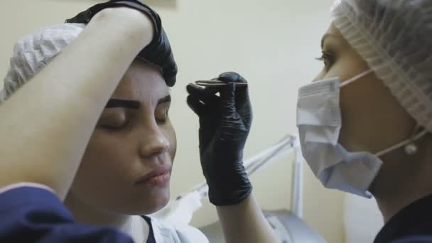 El empleado de la clínica de cosmetología hace manipulaciones en la coloración de las cejas — Vídeo de stock