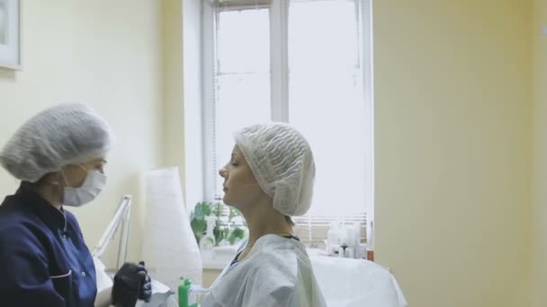 Uma funcionária de uma clínica de cosmetologia faz marcação antes do procedimento de microjateamento — Vídeo de Stock