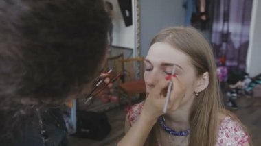 Çok güzel bir kız bir fotoğraf Studio için profesyonel makyaj makyaj sanatçısı yapar