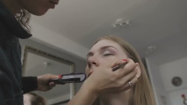 Çok güzel bir kız bir fotoğraf Studio için profesyonel makyaj makyaj sanatçısı yapar