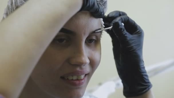 Працівник косметологічної клініки робить маніпуляції по забарвленню брів — стокове відео