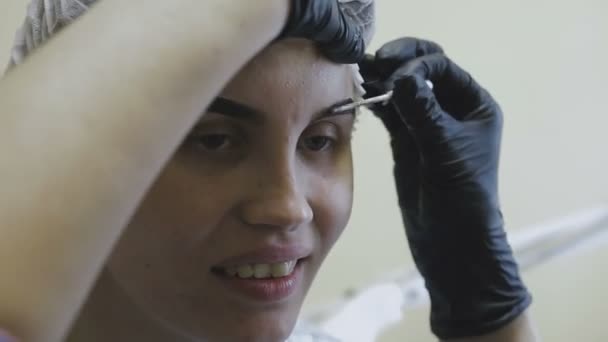 El empleado de la clínica de cosmetología hace manipulaciones en la coloración de las cejas — Vídeo de stock