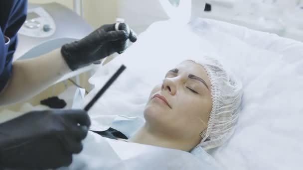 Жінка-працівник косметологічної клініки робить мікропідривну процедуру для пацієнта — стокове відео