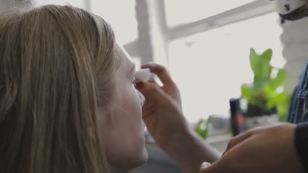 Визажист делает профессиональный макияж для очень красивой девушки в фотостудии — стоковое видео