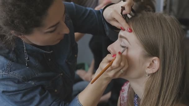 Visagist maakt een professionele make-up voor een heel mooi meisje in een fotostudio — Stockvideo