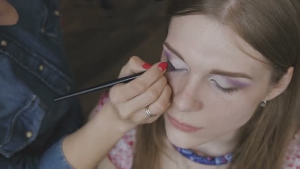 Maquillaje artista hace un maquillaje profesional para una chica muy hermosa en un estudio de fotografía — Vídeos de Stock