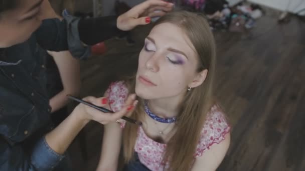 Visagistin macht ein professionelles Make-up für ein sehr schönes Mädchen in einem Fotostudio — Stockvideo