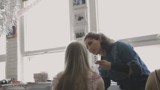 Maquillaje artista hace un maquillaje profesional para una chica muy hermosa en un estudio de fotografía — Vídeo de stock