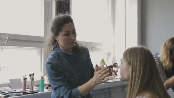 Make-up artist fait un maquillage professionnel pour une très belle fille dans un studio photo — Video