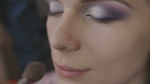 Maquillaje artista hace un maquillaje profesional para una chica muy hermosa en un estudio de fotografía — Vídeo de stock