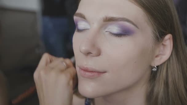 Make-up artist κάνει ένα επαγγελματικό make-up για ένα πολύ όμορφο κορίτσι σε ένα στούντιο φωτογραφίας — Αρχείο Βίντεο
