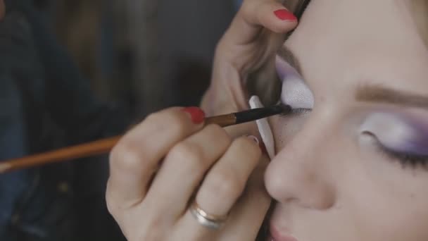 Visagist maakt een professionele make-up voor een heel mooi meisje in een fotostudio — Stockvideo