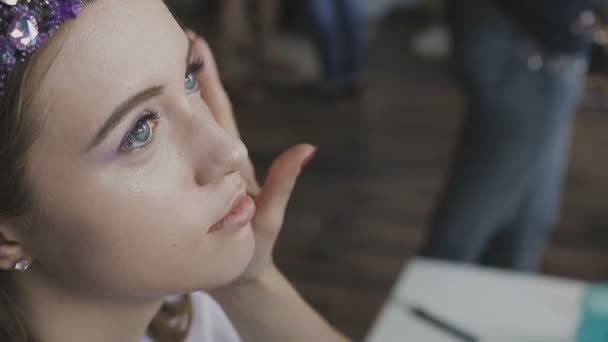 Maquiagem artista faz uma maquiagem profissional para uma menina muito bonita em um estúdio de fotos — Vídeo de Stock