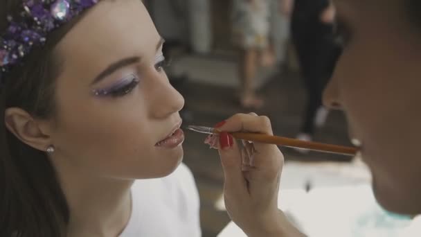 Maquiagem artista faz uma maquiagem profissional para uma menina muito bonita em um estúdio de fotos — Vídeo de Stock