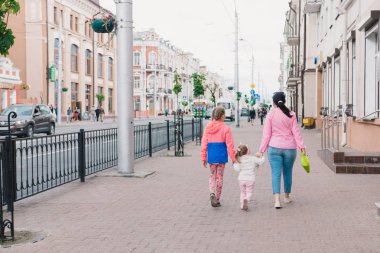 Mutlu anne ve çocukları şehrin çevresinde güneşli bir günde yürüyor