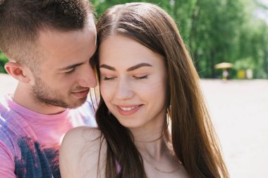 Genç çift, sarılma ve nehir kıyısında birbirlerine gülümsüyor. Kumlu sahilde yürüyüş