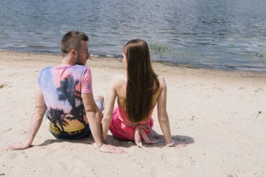 Genç çift, sarılma ve nehir kıyısında birbirlerine gülümsüyor. Kumlu sahilde yürüyüş