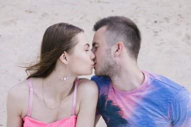 Genç çift, sarılma ve nehir kıyısında birbirlerine gülümsüyor. Kumlu sahilde yürüyüş