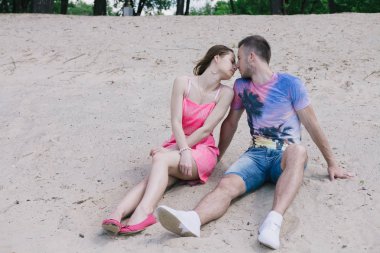 Genç çift, sarılma ve nehir kıyısında birbirlerine gülümsüyor. Kumlu sahilde yürüyüş