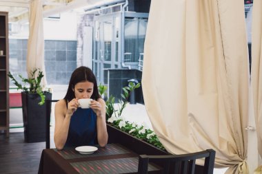 Çok güzel bir iş kadını bir kafede oturur ve bir fincan kahve onun elinde tutan