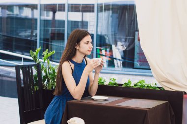 Çok güzel bir iş kadını bir kafede oturur ve bir fincan kahve onun elinde tutan