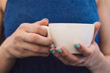 Çok güzel bir iş kadını bir kafede oturur ve bir fincan kahve onun elinde tutan