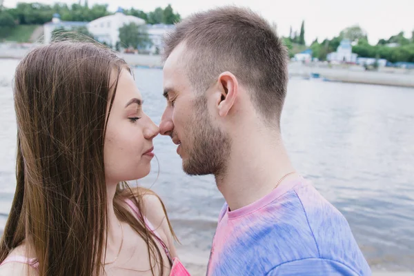 Jong (echt) paar knuffelen en glimlachen naar elkaar op de rivieroever. Wandelen langs het zandstrand — Stockfoto