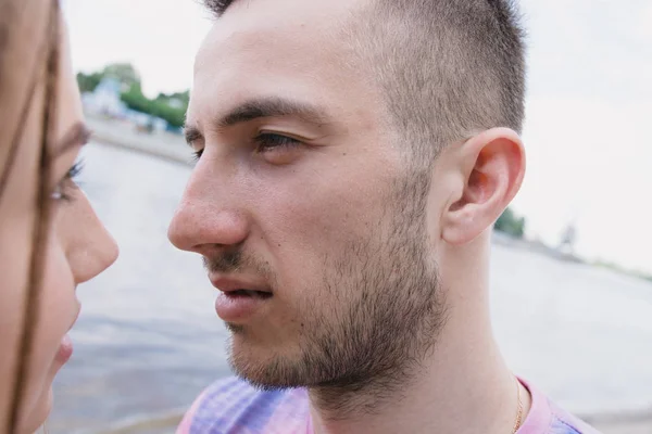 Mladý pár, objímání a usmívají se na sebe na břehu řeky. Procházky podél písečné pláže — Stock fotografie