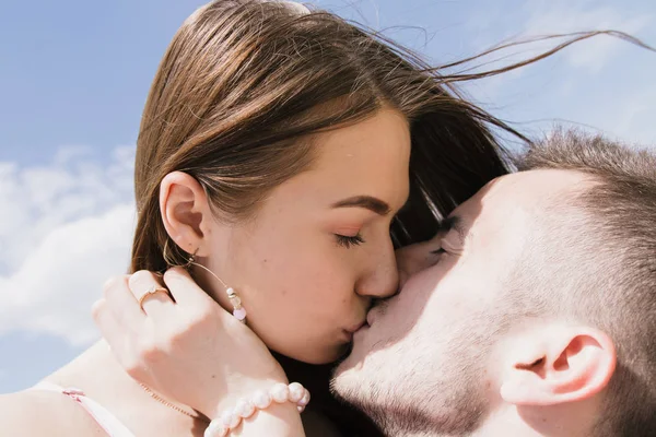 Pareja joven abrazándose y sonriéndose en la orilla del río. Caminando por la playa de arena —  Fotos de Stock