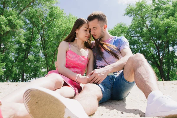 Young couple hugging and smiling at each other on the river bank. Walking along the sandy beach — Stock Photo, Image