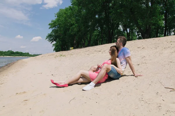 Mladý pár, objímání a usmívají se na sebe na břehu řeky. Procházky podél písečné pláže — Stock fotografie