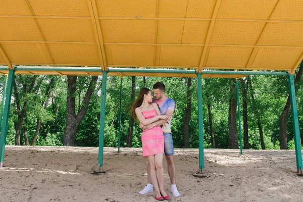 Casal jovem abraçando e sorrindo um para o outro sob um dossel na praia — Fotografia de Stock