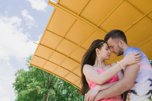 Casal jovem abraçando e sorrindo um para o outro sob um dossel na praia — Fotografia de Stock