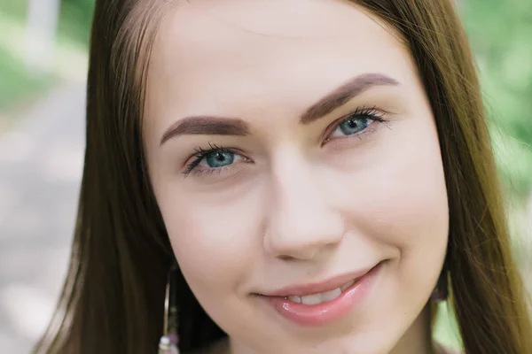 Retrato de una hermosa joven en un claro día soleado. Árboles verdes — Foto de Stock