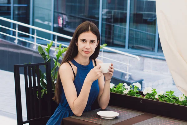 Çok güzel bir iş kadını bir kafede oturur ve bir fincan kahve onun elinde tutan — Stok fotoğraf