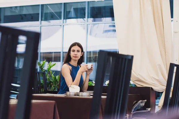Una mujer de negocios muy hermosa se sienta en un café y sostiene una taza de café en sus manos — Foto de Stock
