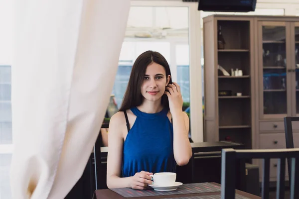 Una mujer de negocios muy hermosa se sienta en un café y sostiene una taza de café en sus manos — Foto de Stock