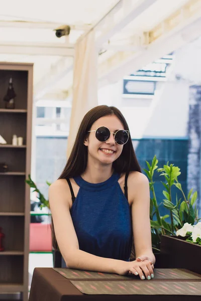 Очень красивая девушка сидит в кафе в черных круглых очках — стоковое фото