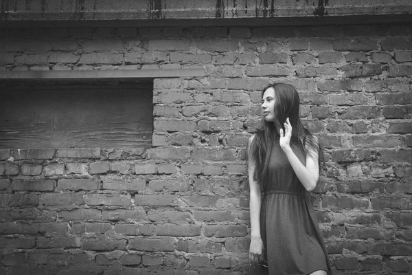 Ein sehr schönes und fröhliches Mädchen steht auf der Straße neben einer Ziegelmauer — Stockfoto