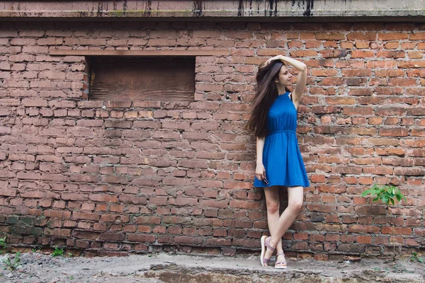 Очень красивая и веселая девушка стоит на улице рядом с кирпичной стеной — стоковое фото