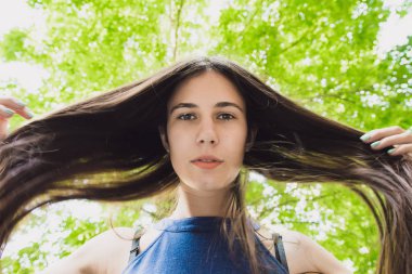 Çok güzel ve neşeli kız uzun, lüks saçlı sokakta duruyor