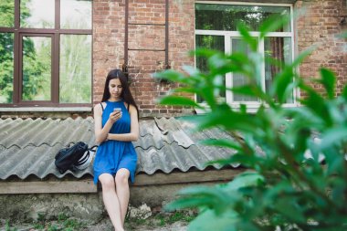 Çok güzel ve neşeli kız uzun, lüks saçlı sokakta duruyor ve onun telefon ile oturur