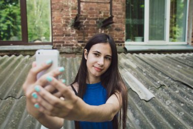 Çok güzel ve neşeli kız uzun, lüks saçlı sokakta duruyor ve bir selfie yapar