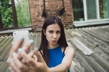 Çok güzel ve neşeli kız uzun, lüks saçlı sokakta duruyor ve bir selfie yapar