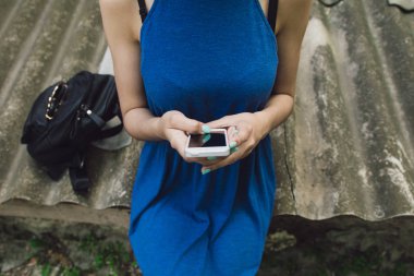 Çok güzel ve neşeli kız uzun, lüks saçlı sokakta duruyor ve onun telefon ile oturur