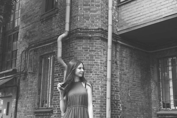 Ein sehr schönes und fröhliches Mädchen steht auf der Straße neben einer Ziegelmauer — Stockfoto