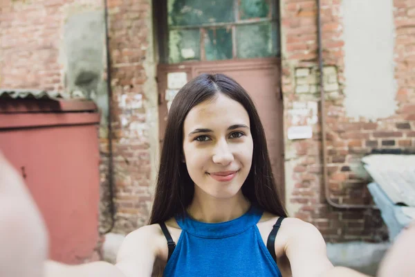 Una chica muy hermosa y alegre se para en la calle con el pelo largo y lujoso y hace una selfie — Foto de Stock