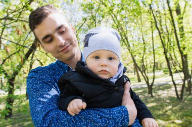 Mutlu genç aile dışarıda yeşil doğada birlikte vakit geçiriyor.